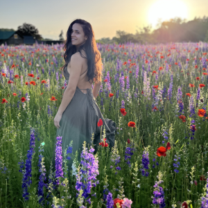 Photo of Hannah Procell standing in a field of flowers.