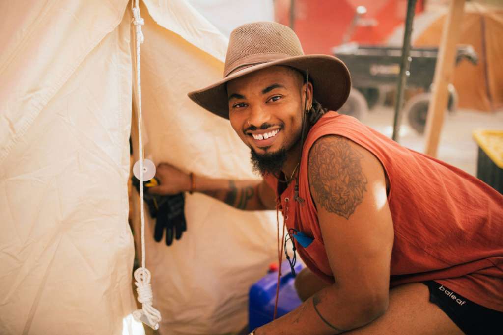 A Zendo Project volunteer smiles at the camera while entering a tent.
